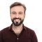 Close up portrait of a smiling young bearded man looking at camera and laughing isolated over white background